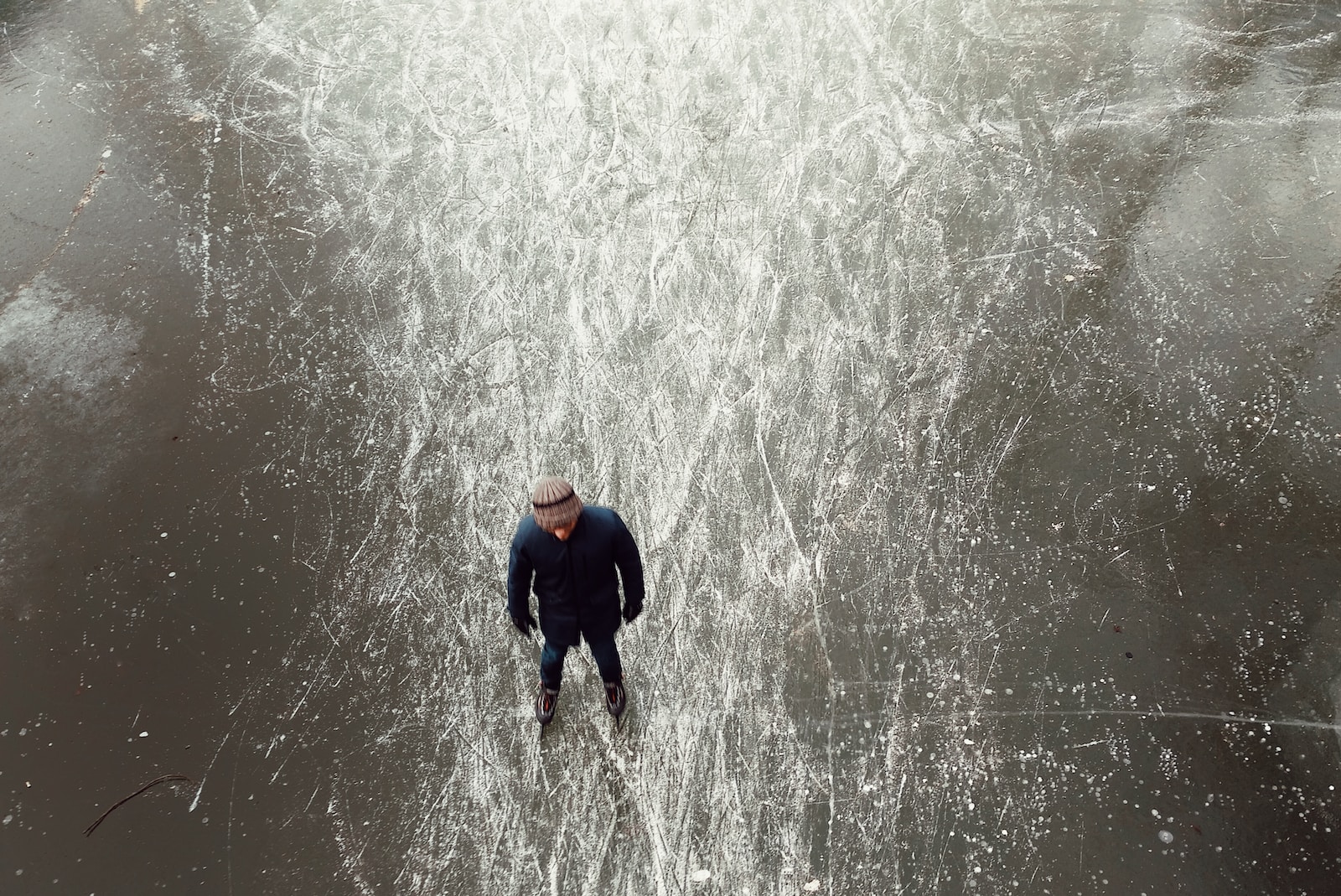 man wearing black jacket standing on frozen body of water during daytime