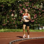 Middle aged female athlete in sportswear running during track and field competition while looking forward