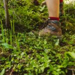 person wearing hiking shoes standing on green grass