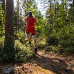 a man in red running through a forest