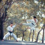 two men performing karate near trees during daytime
