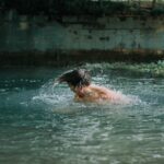 man swimming on water during daytime