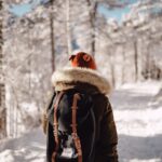 person walking on forest trail covered with snow